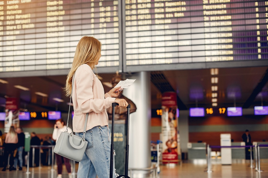 Girl in a airport. Blonde with a documents. Lady in a black t-shirt